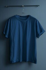 Plain Blue T-Shirt Hanging on Metal Bar Against Dark Background, Simple Fashion and Apparel Display