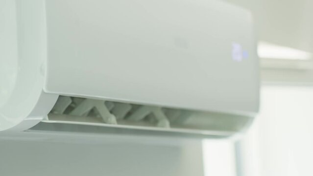 Air conditioner mounted on white wall in modern apartment. Cooling system for comfortable temperature in living room
