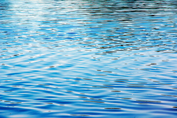 Water ripple texture background. Wavy water surface during sunset, golden light reflecting in the water