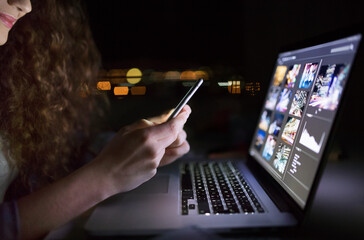 Close up of university student is writing her thesis on a laptop at night, sitting at home at table, focusing on her research. Preparing for final exam, studying.