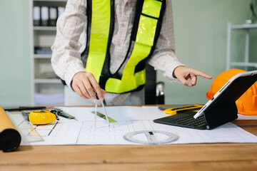 Businessman hand working and laptop with on on architectural project at construction site