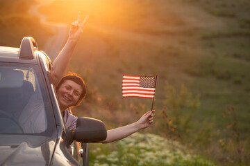 Woma in the car holding a waving american USA flag.