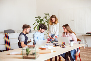 Young group of colleagues working on a new project together in a startup company office. Working in co-working space.