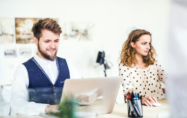 Two colleagues working on a new project together in a startup company office. Working in co-working space.