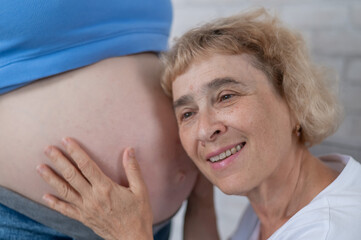 An elderly woman leans against the belly of her pregnant daughter. Close-up.