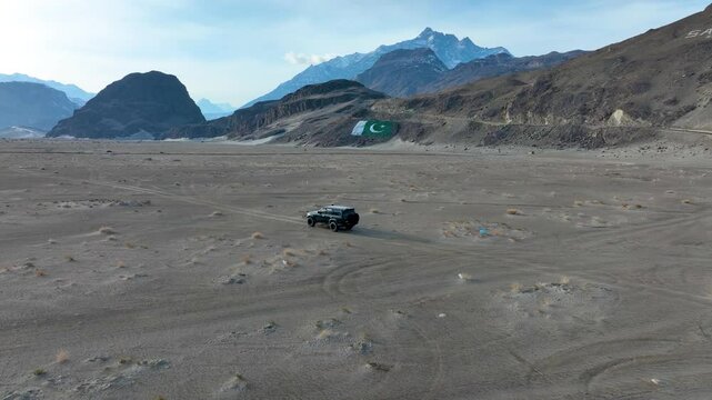 Off-road vehicle traversing Sarfaranga Cold Desert with a Pakistan flag in Skardu Valley.