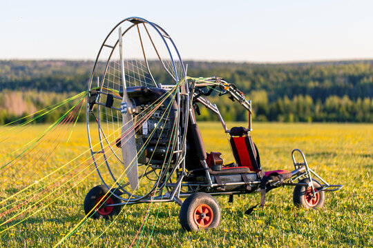 Paragliding machine for paragliding flights on green grass against the bright sun. Preparing paralet with a gasoline engine for flights. Extreme sports