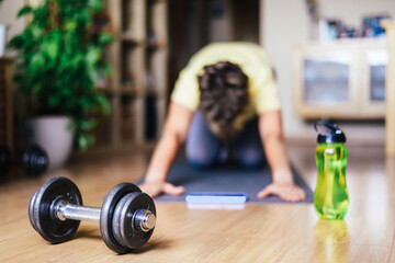 Healthy Lifestyle. Woman At Home Doing Sports Training Stretching In Early Morning, Using Dumbbells And Mat, Wearing Sportswear In Yellow And Green Tones. Morning Routine And Keeping Fit.