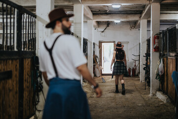 A couple in casual outfits and hats walking through horse stables, exploring the rural setting and experiencing farm life.