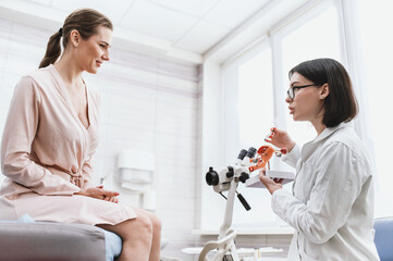 Medical examination in a gynecologist's chair, the doctor shows and explains the genital organs of women. the doctor shows a silicone demonstration model of the female reproductive system (uterus, vag