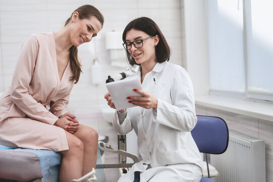 woman doctor look microscope at gynecologist's appointment. Female gynecologist examining patient on chair with equipment. doctor shows test results to patient and explains treatment strategy