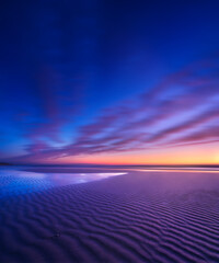 Seascape during sunrise. Long exposure. Lines of sand on the seashore. Bright sky during sunset. A...