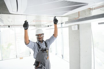 Professional repairman installing air conditioner in a room