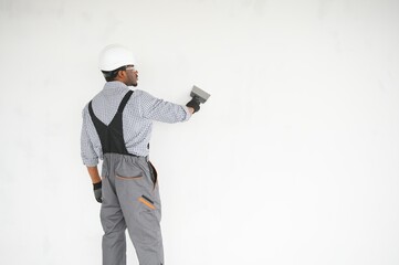 African american Plasterer in working uniform plastering the wall indoors