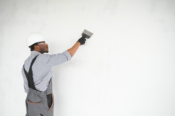 African american Plasterer in working uniform plastering the wall indoors