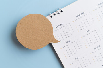 top view of real blank grunge brown paper cut on blurred yearly calendar on blue background for important, reminder concept