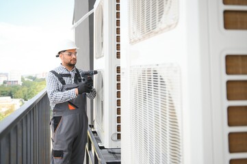 Young indian man repairman checking an outside air conditioner unit