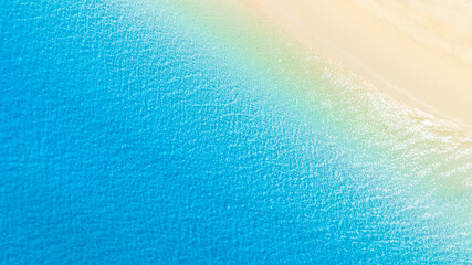 Top view of sandy beach for summer vacation concept. Nature of the beach and sea in summer with sunlight, and light sand. The sea sparkles against the blue sky. Sandy Beach for summer vacation concept