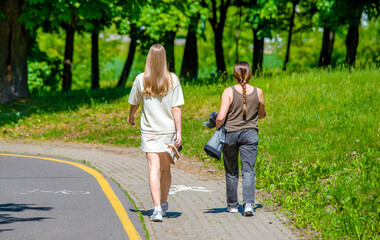 Two girlfriends walk along a path in the Park
