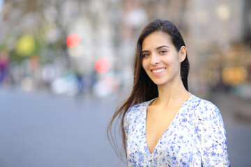 Happy woman looking at camera with perfect smile in the street