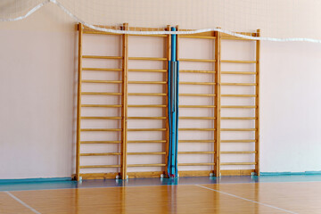 Swedish ladder and extendable volleyball net against a wall, promoting fitness and play
