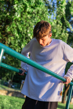 Young Man Exercising on Parallel Bars in Park on Sunny Day