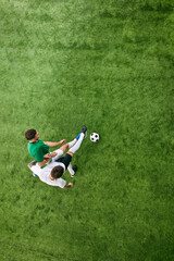 Fototapeta premium Aerial view. Two players vie for the ball in action on green lush playground. Tense moment in soccer match. Concept of professional sport, championship, final match, movement. Ad