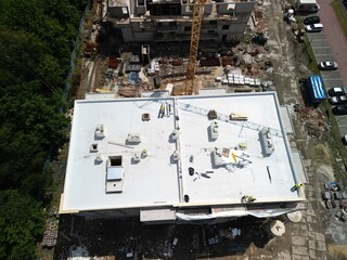 Distant and Dark Tilted View of Construction Site with Flat Roof A distant and dark tilted photograph captures a construction site of a building with a flat roof. The image shows building materials sc