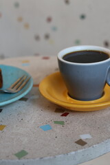 cup of coffee or tea and dessert in coffee shop or restaurant. Drink fragrant black drink during break. modern coffee shop, fresh roasting of coffee beans. grey mug and yellow saucer, colored dishes
