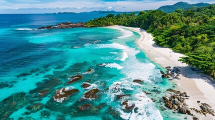 Obraz premium A breathtaking aerial top view of an idyllic white sand beach surrounded by lush green forests and crystal-clear turquoise waters, with gentle waves crashing against rocky outcrops, creating a serene