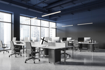 Dark coworking interior with pc monitors on desks in row, panoramic window
