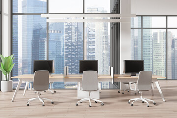 Modern office coworking interior with pc monitors on tables, panoramic window