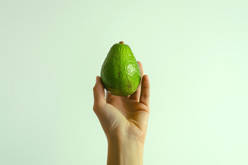 Person hand hold avocado fruit isolated on green background.