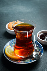 Traditional Turkish serving of aromatic tea in a glass. On a black stone background.