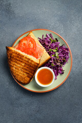 Sandwich with salmon, tomatoes and purple cabbage salad. Close up.
