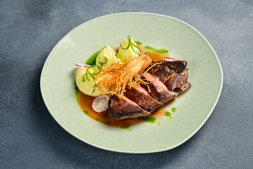 Veal steak with enoki mushrooms and potatoes. In a plate. Restaurant dish. Close up.