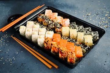 A large set of colored sushi and rolls in a plastic box. Japanese food. Food delivery. close up
