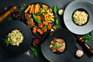 Set of food and dishes in plates on a black stone background. Salads, pasta and snacks. Food background.