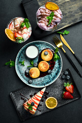 Background of desserts. Cheesecake, cheese pancakes and ice cream. On a black stone background.
