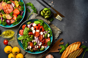 Fresh summer salad: tomatoes, mozzarella cheese, basil and olives. Caprese. On a gray concrete background.