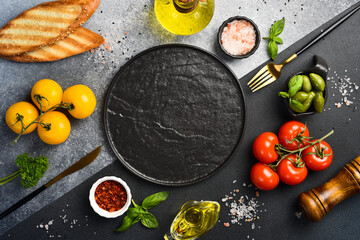Black stone cooking background. Spices and vegetables. Top view. Free space for your text.