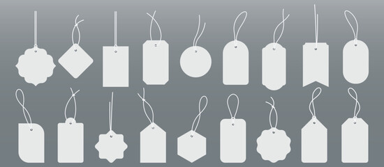 Blank price tags with strings hang against gray.Suitable for retail, pricing, sales, discounts, promotions, merchandise, multipurpose design projects.