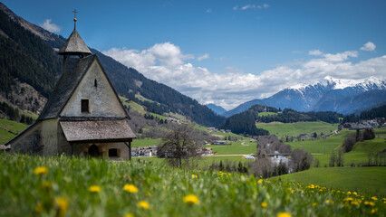 Beautiful scenery of an old church between mountains and yellow flowers in sterzing south tirol