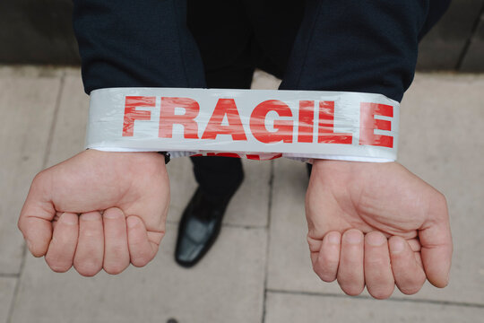 Hands of businessman wrapped with fragile caution tape