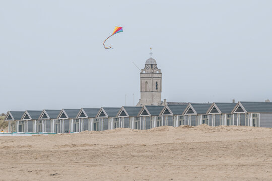 Netherlands, South Holland, Katwijk aan Zee, Kite flying over row of beach huts in front of Andreaskerk church