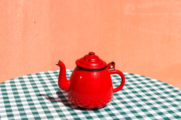 Red color tea kettle on table cloth at terrace