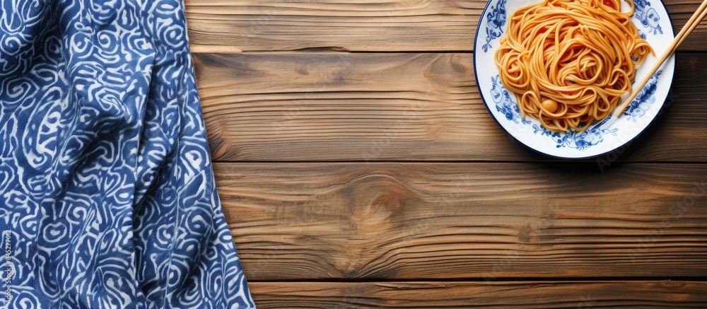 Poster a top down view of a plate of noodles on a wooden table accompanied by wooden chopsticks set against