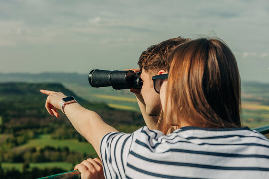 Young couple looking through binoculars from observation point