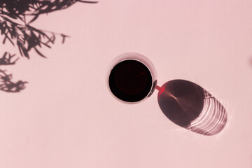 Elegant glass of red wine, in harsh summer sunlight, with marked shadow. Minimal style. Copy space.