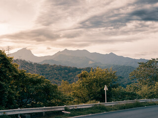 rolling mountain and clouds and trees and road side